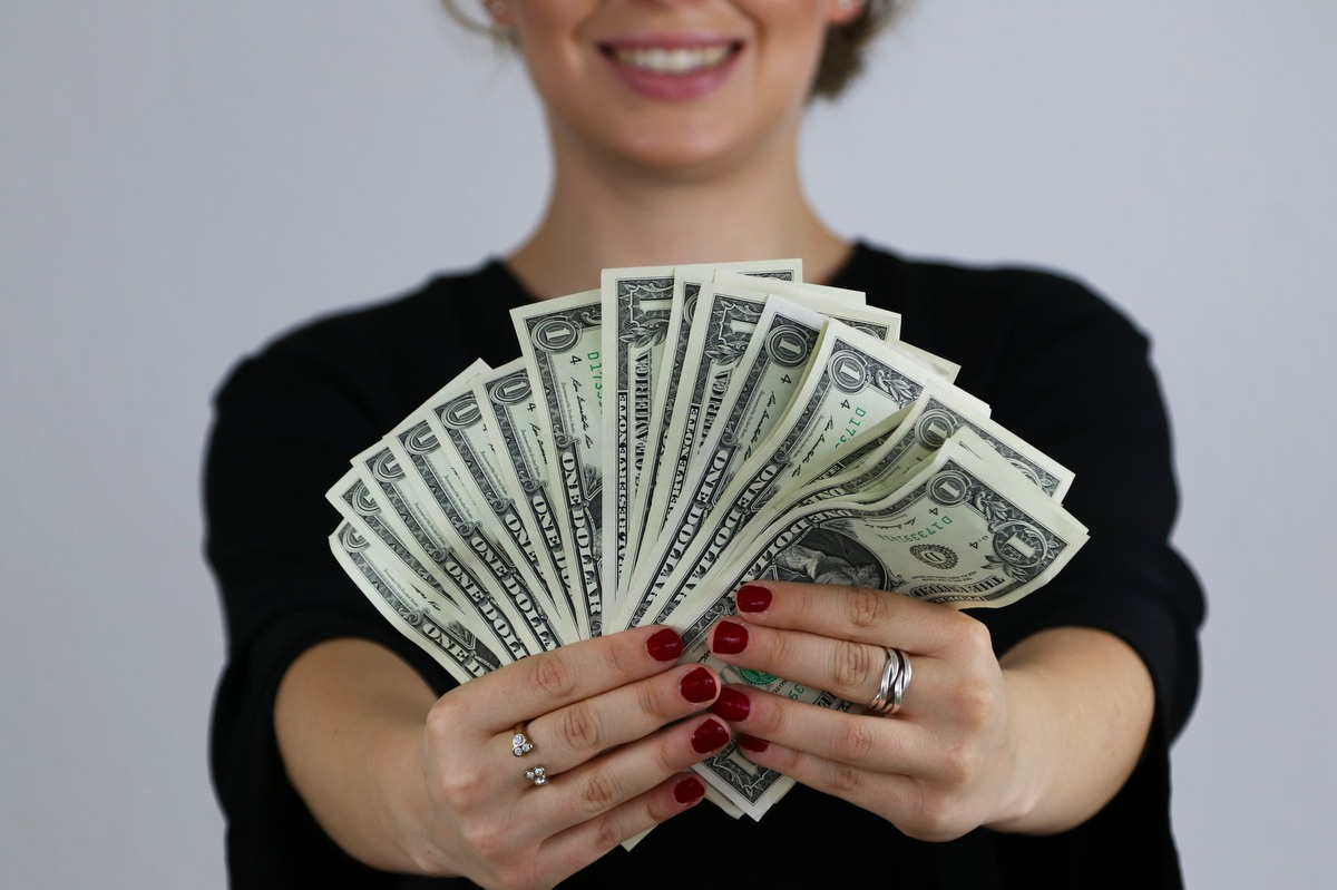 Female business owner holding dollar bills after maximizing revenue with her point of sale system